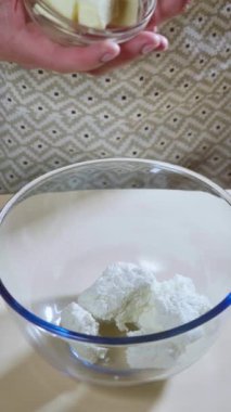 Dikey ekran. Yemek hazırlama. Bir kadın, kurabiye yapmak için tereyağını cam bir kaseye koyar. Yavaş çekim 100 fp. Yüksek kaliteli FullHD görüntüler