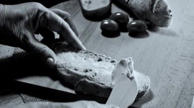 Koyu ciabatta ekmeğine ahşap bıçakla krem peynir sürüyorum. Yüksek kaliteli FullHD görüntüler