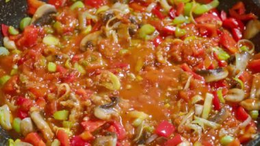 Yemek hazırlama. Doğranmış sebzeler, kereviz sapları, pırasalar, mantarlar, domates sosunda fokurdayan kırmızı dolma biberler tavada sotelenir..