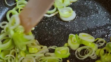 Yemek hazırlama. Doğranmış sebze, pırasa zeytinyağlı sıcak tavada kızartılır. Seçici odaklanma. Yavaş çekim. Yüksek kaliteli FullHD görüntüler