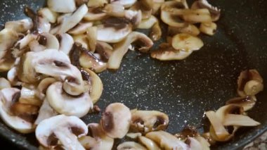 Kavurma Şampiyonları mantarı. Aşçı mantarları ahşap bir spatulayla tavada karıştırır..