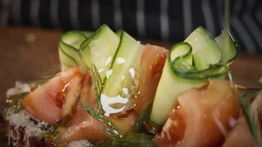 Yemek hazırlama. Şef salatalık ve domatesli sandviçe zeytinyağı döker. Yavaş çekim 50 fp. Yüksek kalite 4k görüntü