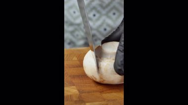 Yemek hazırlama. Tahta kesme tahtasıyla taze şampiyon mantarları kesmeye yakın çekim. Seçili odak. Yavaş çekim 50fps. Yüksek kalite 4k görüntü