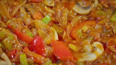Yemek hazırlama. Çeşitli sebzeler bir tavada pişirilir. Paprika, mantar, kereviz, pırasa vs. Yavaş çekim 50fps. Seçici odaklanma. Yüksek kalite 4k görüntü