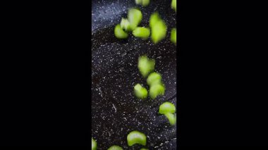 Dikey ekran video. Yemek hazırlama. Şef yemek pişirmek için dilimlenmiş, kereviz saplarını sıcak tavaya koyar. Seçici odaklanma. Yavaş çekim 50fps. Yüksek kalite 4k görüntü