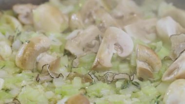 Yemek hazırlama. Tavada pişen yemek malzemelerinin yakın çekimi. Mantar, soğan, yağ, kereviz sapı. Makarna ya da spagetti için mantar sosu yapma süreci. Yüksek kalite 4k görüntü
