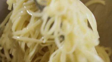 Yemek hazırlama. Bir aşçı metal bir kasede zeytinyağıyla spagetti karıştırmak için metal maşa kullanır..