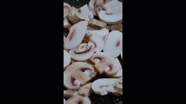 Dikey görüntü. Kavurma Şampiyonları mantarı. Aşçı sıcak tavaya çiğ mantar koyar..