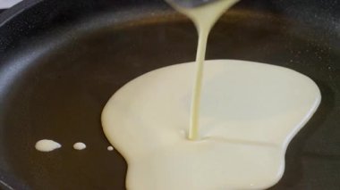 Yemek hazırlama. Yaklaş, ince krep pişir, krep yap. Hamur sıcak tavaya düşer. Yüksek kalite 4k görüntü