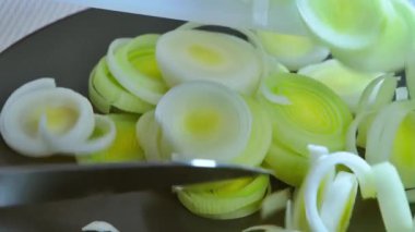 Yemek hazırlama. Dilimlenmiş pırasa tabağa konur. Yavaş çekim videosu 100fps. Yüksek kaliteli FullHD görüntüler