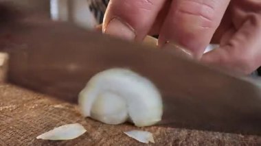 Aşçı ahşap bir tahtanın üzerinde bir bıçakla soğan keser. Seçici odaklanma. Yavaş çekim video 50 fps. Yüksek kalite 4k görüntü
