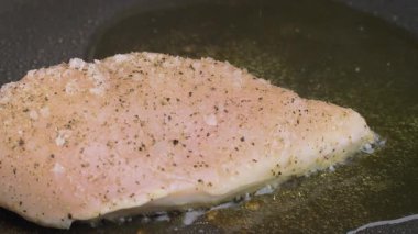 Bir aşçı büyük miktarda kızgın yağda bir parça tavuk filetosu kızartıyor. Yavaş çekim videosu, kızgın yağ tavanın üstünde çatırdıyor. Yüksek kalite 4k görüntü