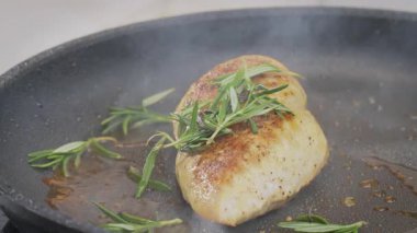 Bir şef tavada bir parça tavuk filetosu pişiriyor ve tavaya kekik döküyor. Yavaş çekim 100 fp. Yüksek kalite 4k görüntü