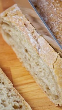 Dikey görüntü. Ciabatta ekmeğini ekmek bıçağıyla doğrarken yakın plan..