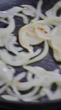 Tavada doğranmış soğan. Aşçı soğanları karıştırmak için tavayı sallar..