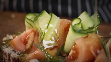 Yemek hazırlama. Şef salatalık ve domatesli sandviçe zeytinyağı döker. Yavaş çekim 50 fp. Yüksek kalite 4k görüntü