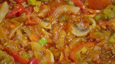 Yemek hazırlama. Çeşitli sebzeler bir tavada pişirilir. Paprika, mantar, kereviz, pırasa vs. Yavaş çekim 50fps. Seçici odaklanma. Yüksek kalite 4k görüntü