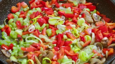Tavada kızartılan sebzelere tuz ekliyorum. Mantar, biber, pırasa, kereviz sapları tavada pişirilir. Yavaş çekim videosu. Yüksek kaliteli FullHD görüntüler