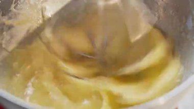 Yemek hazırlama. Modern mutfak mikseri iş başında. Elektrikli mikserde yumurta sarısı ve şekeri yenmek. Yavaş çekim video 50 fps. Yüksek kalite 4k görüntü