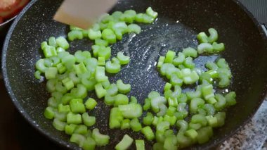 Yemek hazırlama. Kızartma tavasında dilimlenmiş kereviz sapları, sıcak zeytinyağı. Yavaş çekim 100 fp. Yüksek kaliteli FullHD görüntüler