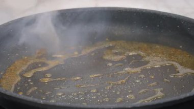 Yemek hazırlama. Kızgın zeytinyağında tavada kızartılmış tavuk filetosunun yakın çekimi. Bir şef tavuk filetosunu metal maşayla kızartıyor. Yavaş çekim videosu 100fps. Yüksek kalite 4k görüntü