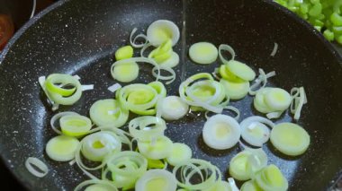 Tavada kızaran pırasa dilimlerine zeytin yağı ekliyorum. Yüksek kaliteli FullHD görüntüler