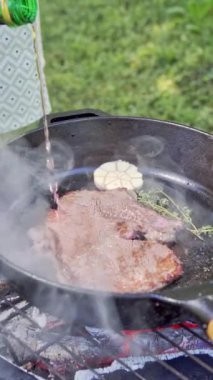 Dikey video. Bifteğin üzerine kırmızı şarap dök. Dökme demir tavada ızgara biftek. Yüksek kaliteli FullHD görüntüler