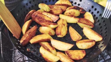 Özel bir ızgara tavasında sebze kızartıyorum. Şef patatesleri ızgara yapar ve onları daha iyi pişirmek için ahşap bir spatula ve çatalla karıştırır. Izgara mevsimi. Yüksek kaliteli FullHD görüntüler