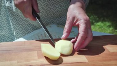 Kızartma için soyulmuş patatesi dört parçaya bölen bir şefin yakın çekimi. Yavaş çekim 100 fp. Yüksek kaliteli FullHD görüntüler