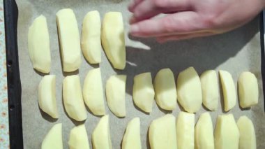 Bir aşçının fırında pişirmek için dilimlenmiş patatesleri fırına koyduğu yakın plan. Yavaş çekim 100 fp. Yüksek kaliteli FullHD görüntüler