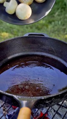 Dikey video. Şef, şampiyon mantarlarını dökme demir bir tavaya doldurur. Izgara. Yavaş çekim 100 fp. Yüksek kaliteli FullHD görüntüler