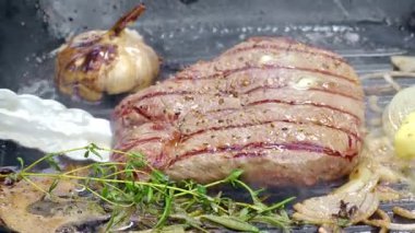 Yemek hazırlama. Bir şef dökme demir bir tavada pişen sulu bir bifteği devirmek için metal maşa kullanır. Yüksek kaliteli FullHD görüntüler