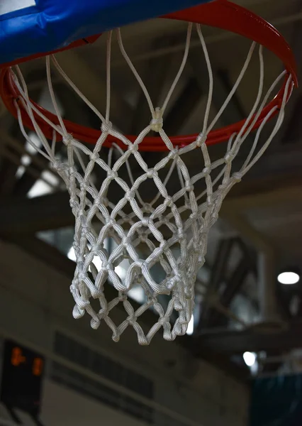 An interior space of a basket ball court showing a basketball ring as a focal point.