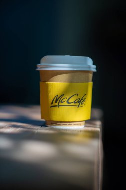 BANGKOK - 11 Aralık 2022: Mc Cafe, güzel bir güneş ışığı kalıbıyla ahşap tezgahın üzerine yerleştirildi. McDonalds 'ın kahve fincanını götürmesi.