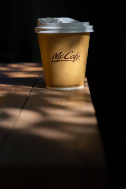 BANGKOK - 11 Aralık 2022: Mc Cafe, güzel bir güneş ışığı kalıbıyla ahşap tezgahın üzerine yerleştirildi. McDonalds 'ın kahve fincanını götürmesi.