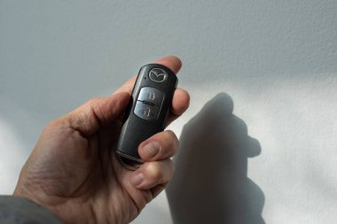 Bangkok, Tayland - 26 Ocak 2023: Güneşli bir günde beyaz bir arka planda Mazda uzaktan kumandalı araba anahtarı tutan bir erkeğin yakın çekimi.