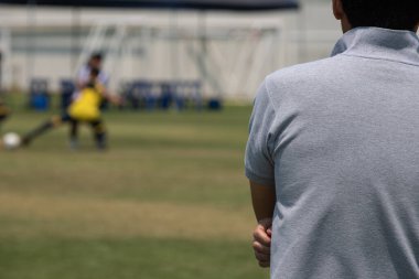 Futbol babaları açık havada ve güneşli bir günde oğlunun okul turnuvasında futbol oynamasını izliyor. Spor, açık hava etkinliği, yaşam tarzı, mutlu aile ve ev hanımı anne ve baba kavramı.