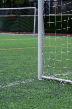 Beyaz alüminyum gol, gençler futbol turnuvası için beyaz ağlı yapay plastik çimen sahası sabah takımların oynamasını ve antrenman yapmasını bekliyor. Arka planda başka bir beyaz hedef.