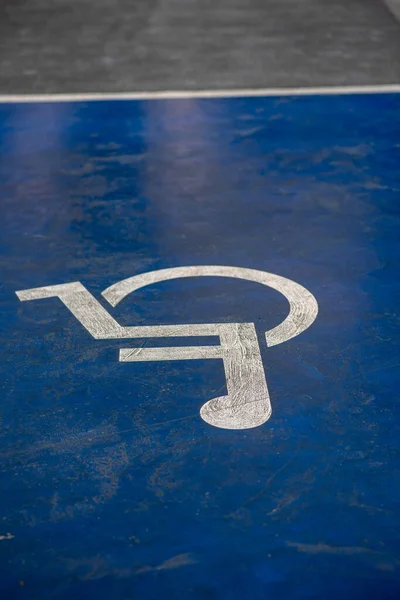 Blue disability parking area with white icon sign painted on the tarmac in the shopping mall indicating parking space for people with special need only.