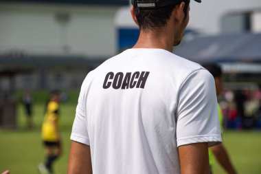 Baba, oğlunun güneşli bir günde bir okul turnuvasındaki futbol maçını seyrediyor. Spor, açık hava etkinliği, yaşam tarzı, mutlu aile ve futbol annesi ve futbolcu baba kavramı..