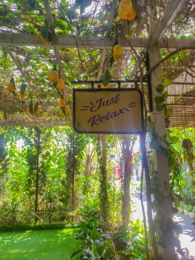 Üzerinde yazı olan sarı bir tabela. Güzel bahçede rahatla.