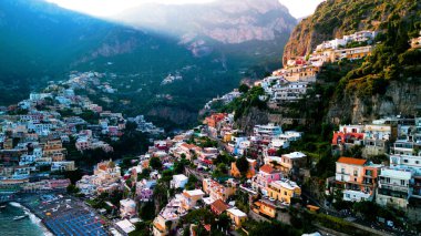 Positano 'nun kıyı cazibesinin muhteşem bir görüntüsü. Uçurumlar ve deniz örnekleri arasında kurulmuş, gök mavisi sulara karşı renkli binalar. Akdeniz cenneti.