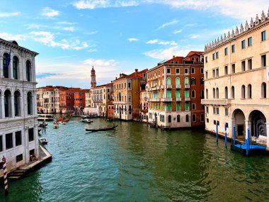 Venedik 'in büyüleyici su yollarının ve zamansız mimarisinin büyüleyici bir görüntüsü. Romantizm içinde yüzen bir şehirde gondolların kemerli köprülerin altında süzüldüğü rüya gibi bir sahne.