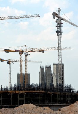 Giza, Mısır, 10 Temmuz 2022: Yeni konut binalarının inşaatı ve vinçlerle yüklenen nesneleri, yüksek gökdelen kulelerini, seçici odaklı kuleleri taşıyan yüksek binalar