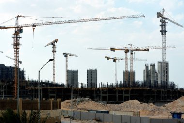 Giza, Mısır, 10 Temmuz 2022: Yeni konut binalarının inşaatı ve vinçlerle yüklenen nesneleri, yüksek gökdelen kulelerini, seçici odaklı kuleleri taşıyan yüksek binalar