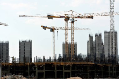 Giza, Mısır, 10 Temmuz 2022: Yeni konut binalarının inşaatı ve vinçlerle yüklenen nesneleri, yüksek gökdelen kulelerini, seçici odaklı kuleleri taşıyan yüksek binalar