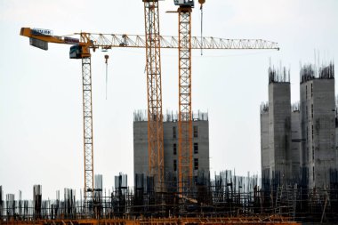 Giza, Mısır, 10 Temmuz 2022: Yeni konut binalarının inşaatı ve vinçlerle yüklenen nesneleri, yüksek gökdelen kulelerini, seçici odaklı kuleleri taşıyan yüksek binalar