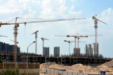 Giza, Mısır, 10 Temmuz 2022: Yeni konut binalarının inşaatı ve vinçlerle yüklenen nesneleri, yüksek gökdelen kulelerini, seçici odaklı kuleleri taşıyan yüksek binalar