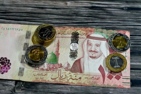 100里亚尔100里亚尔沙特阿拉伯里亚尔现钞和成堆的沙特里亚尔1和2里亚尔现钞 分别印有国王Salman Bin Abdulaziz Saud和国王Abdulaziz的货币兑换率 — 图库照片