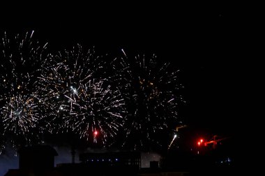 Geceleri bir inşaat alanının gölgesi ve vinçlerle renkli havai fişekler, kutlama işaretleri, yıldönümü karnavalı ve festival konsepti, parlak havai fişeklerin seçici odak noktası